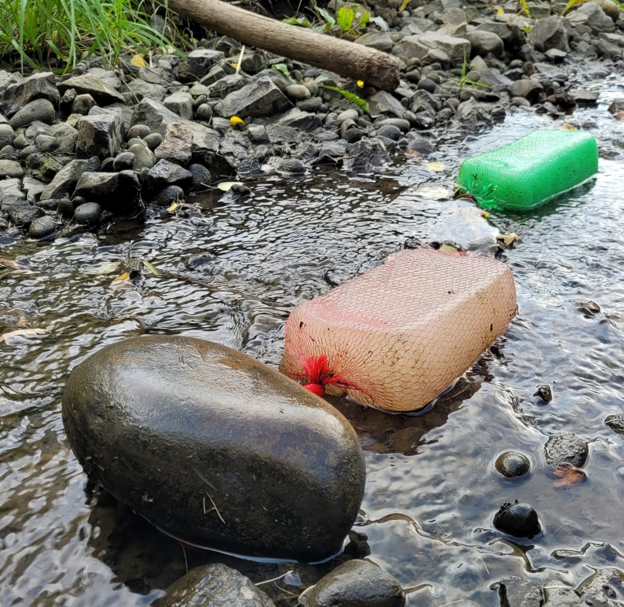 Gel Flocculant blocks in mesh bags resting in a shallow rocky stream